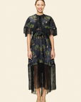 Woman wearing a floral dress with fringe details on a plain background