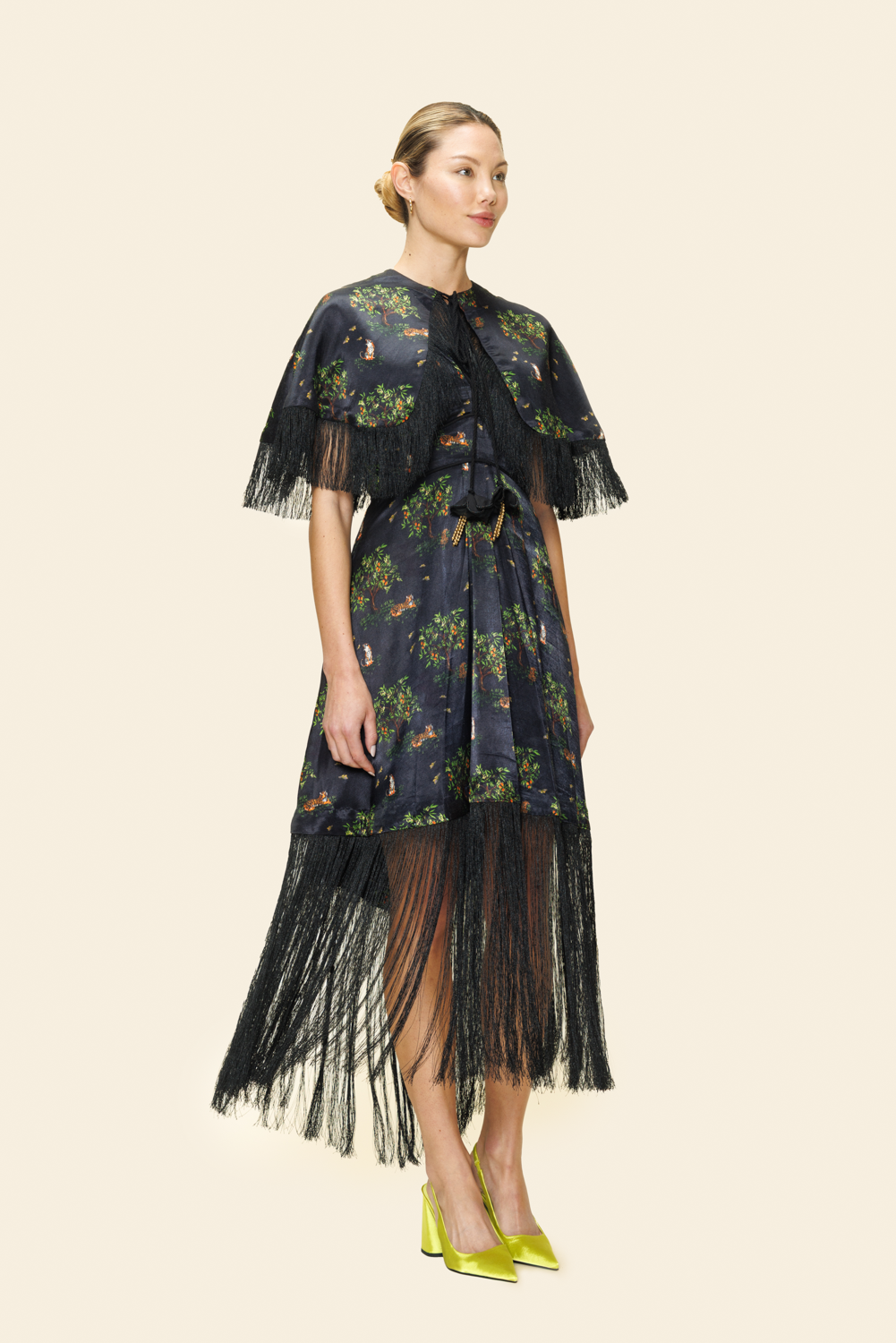 Woman wearing a dark floral dress with fringe details on a light background
