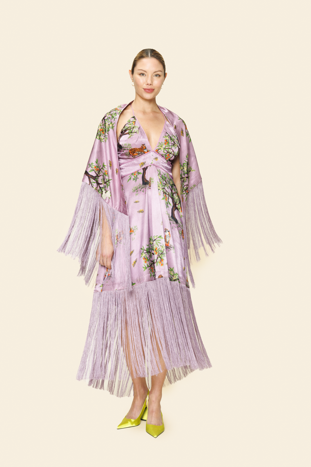 Woman wearing a floral dress with fringe scarf on a plain background