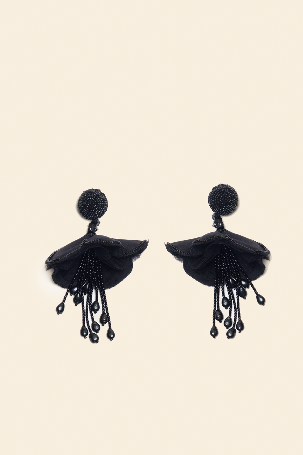 Pair of black beaded floral earrings on a beige background