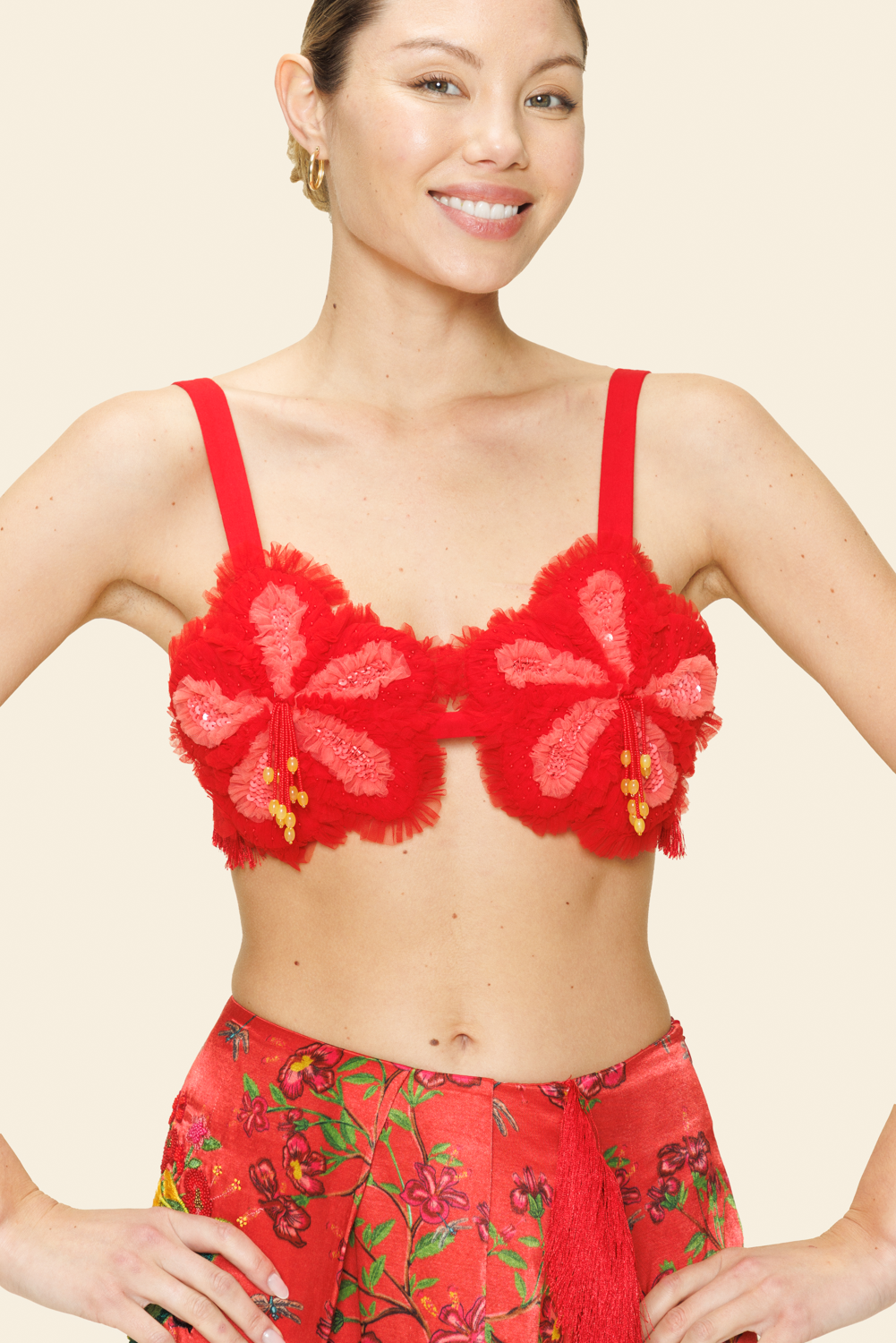 Woman wearing a red floral bralette and skirt against a light background.