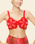Woman wearing a red floral bralette and skirt against a light background.