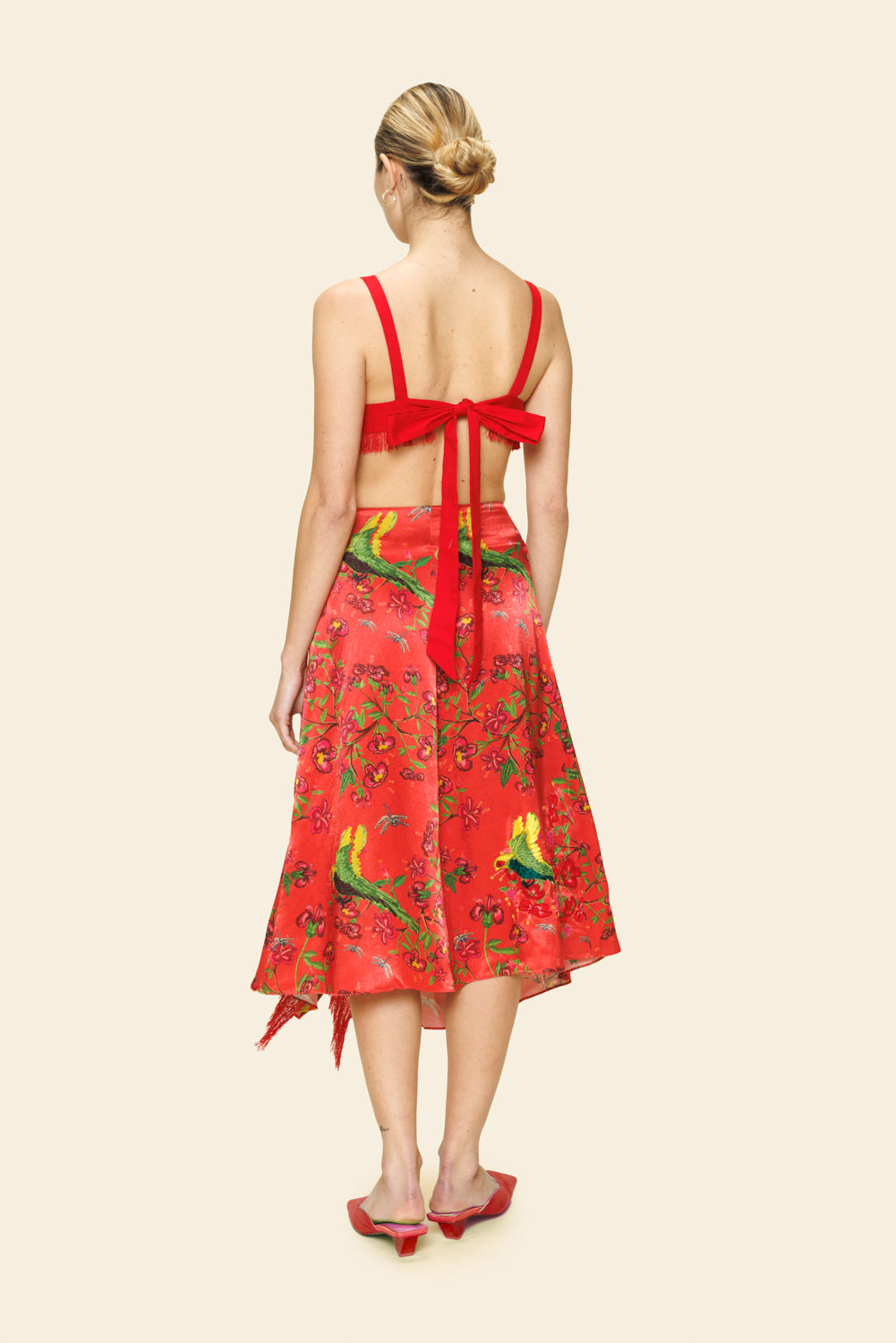 Woman wearing a red skirt with a floral pattern on a beige background