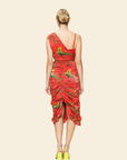 Model wearing a red dress with bird pattern on a beige background seen from the back