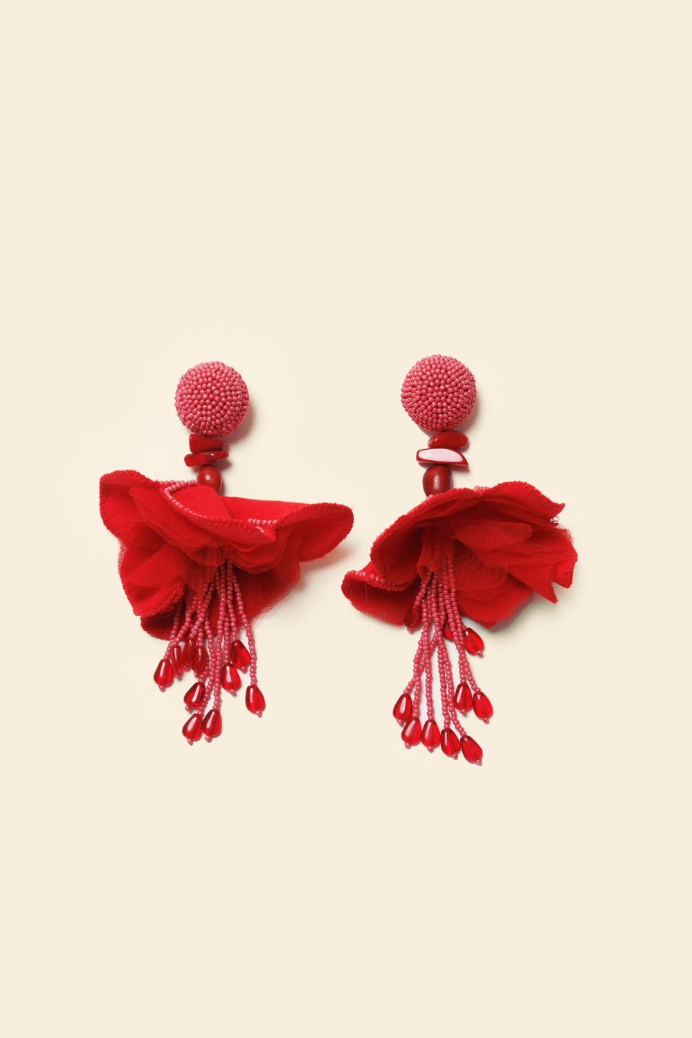 Pair of red tassel earrings on a beige background