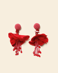 Pair of red tassel earrings on a beige background