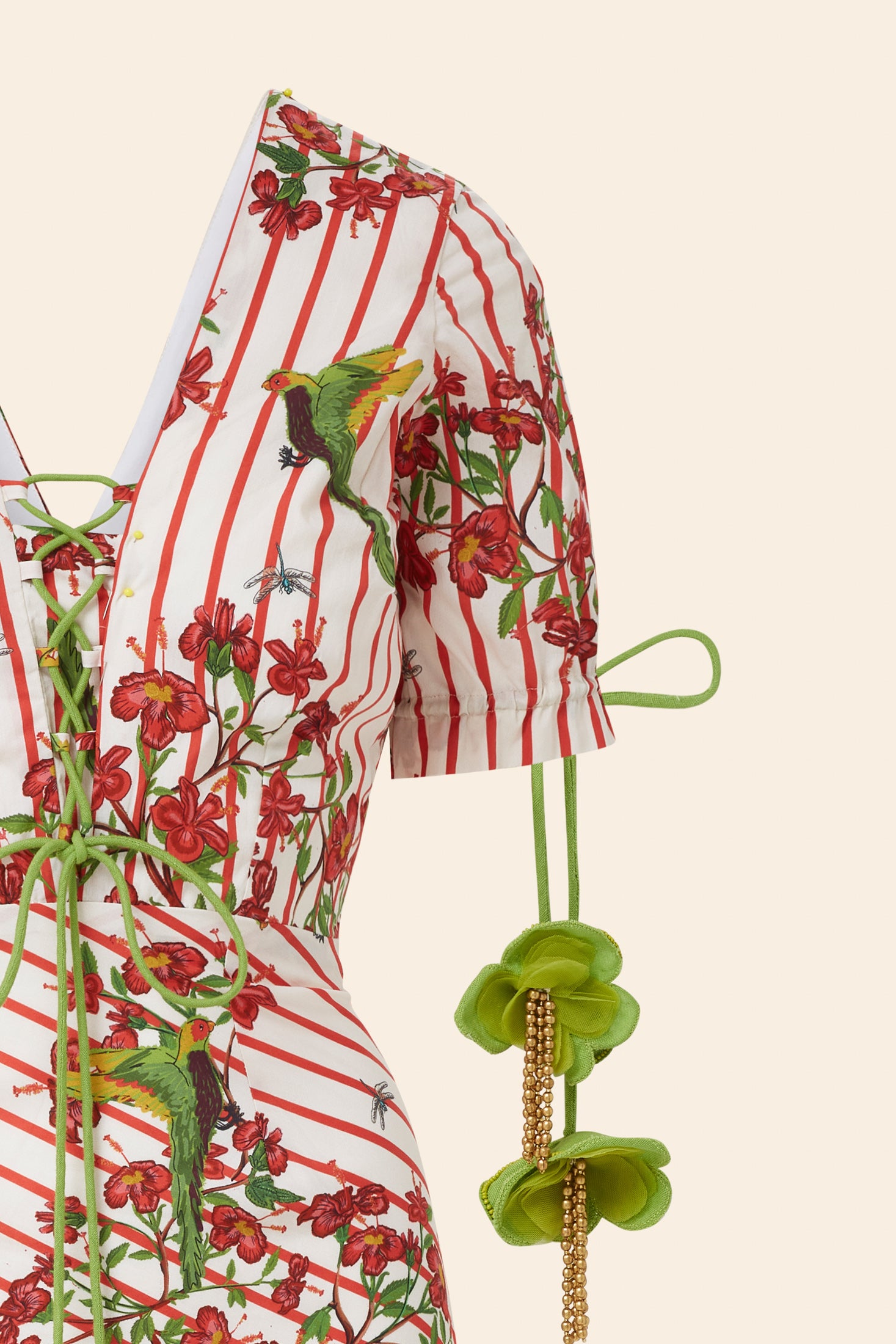 Red and white striped shirt with floral and parrot pattern on a beige background
