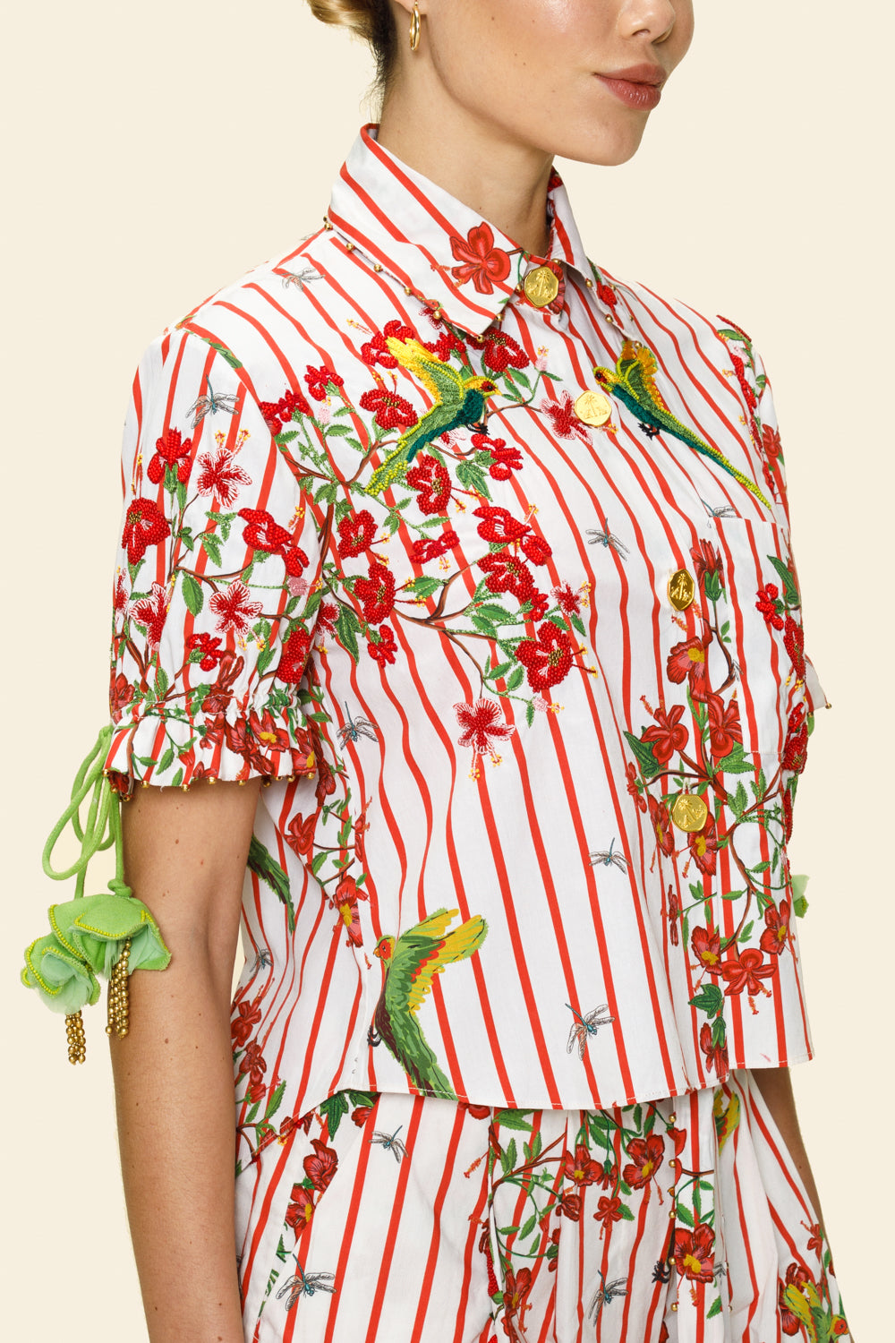 Person wearing a colorful outfit with floral and parrot patterns on a beige background