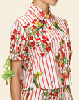 Person wearing a colorful outfit with floral and parrot patterns on a beige background