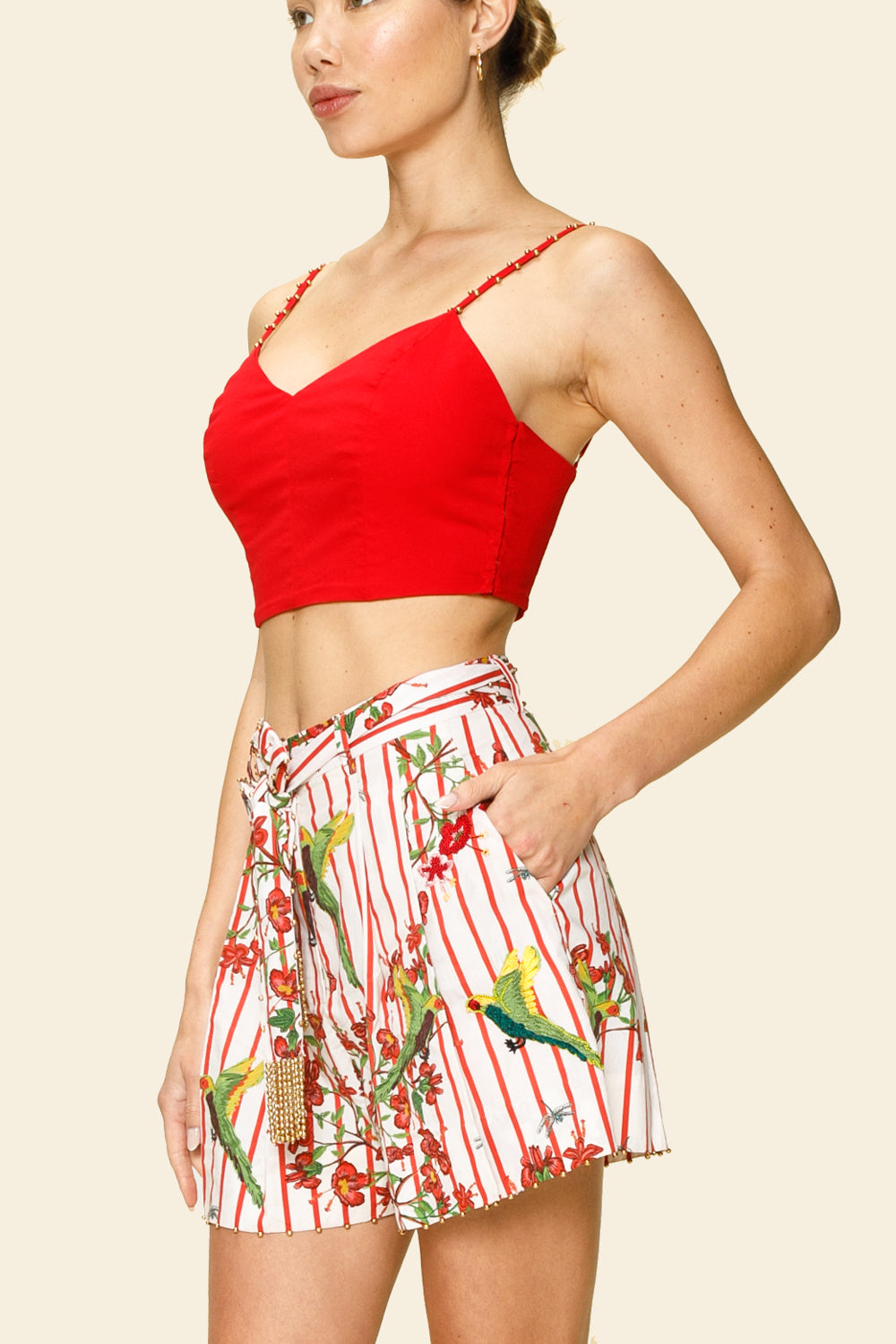 Woman wearing a red top and a floral short on a beige background
