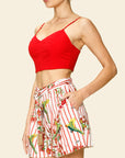 Woman wearing a red top and a floral short on a beige background