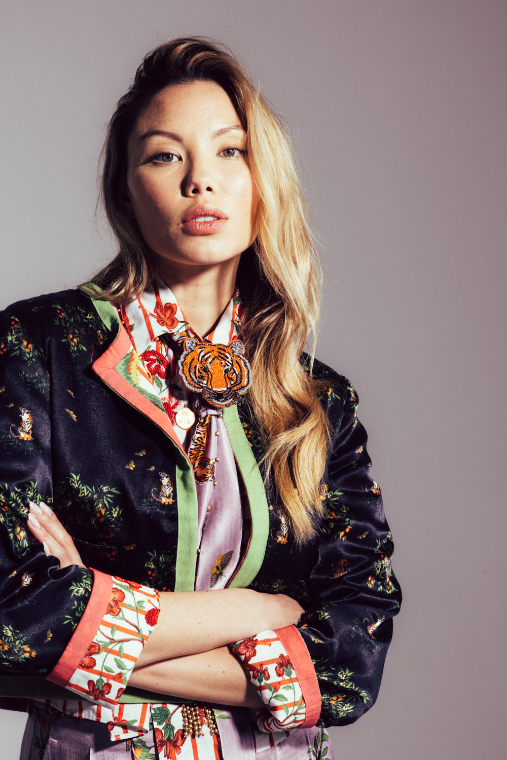 Woman wearing a colorful embroidered jacket with a neutral background