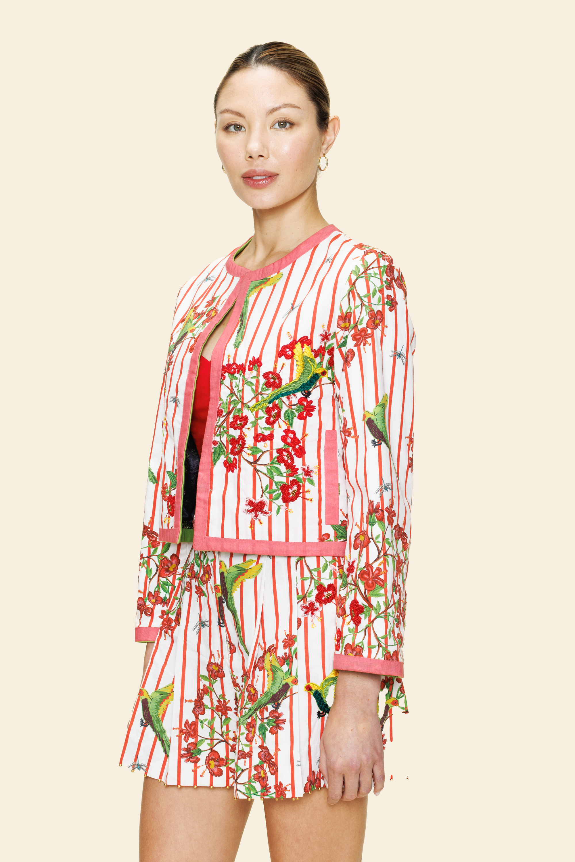 Woman wearing a red and white floral jacket and short on beige background