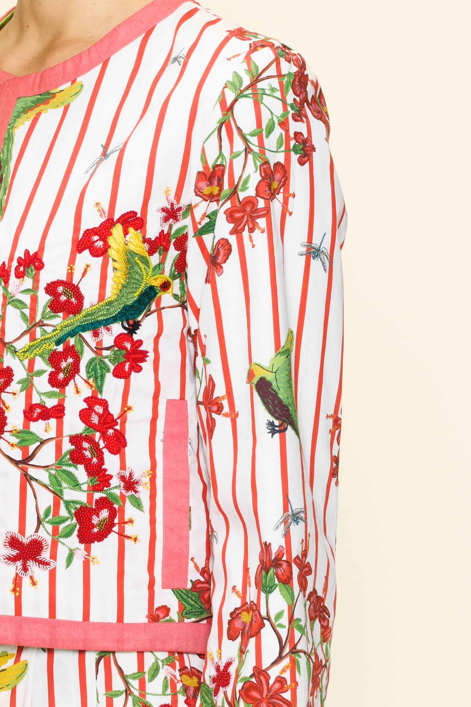 Close-up of a colorful floral and bird patterned fabric with red stripes.