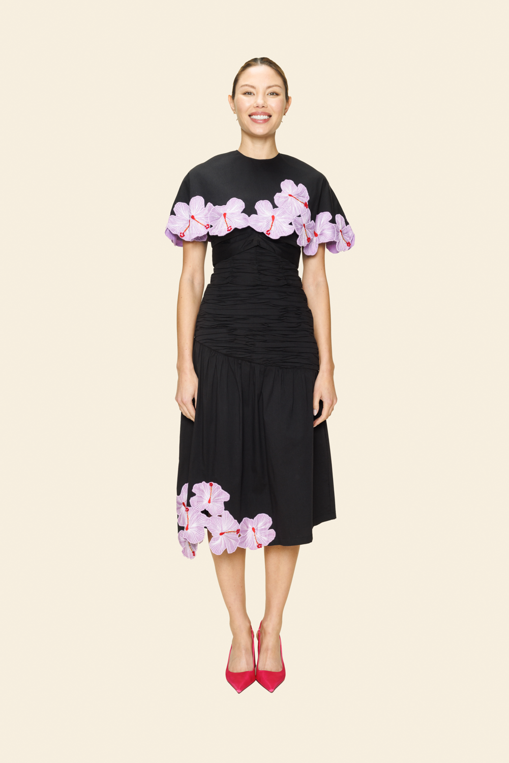 Woman wearing a black skirt and cape with floral appliqué 