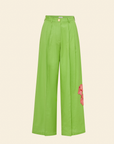 A tailored green cotton-linen trouser with a single hand-embroidered pink hibiscus on the left leg, featuring double front pleats and a fly-front closure.