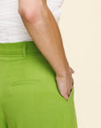 Green pants worn by a person on a beige background