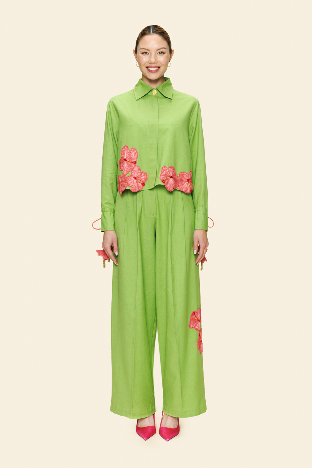 Woman wearing a green outfit with pink floral accents on a light background