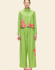 Woman wearing a green outfit with pink floral accents on a light background