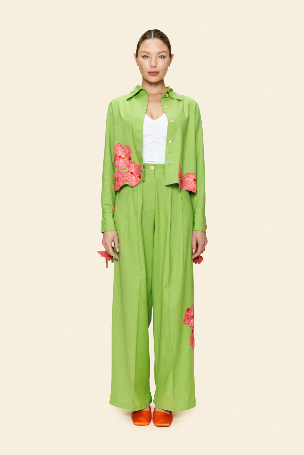 Person wearing a green outfit with floral details on a plain background