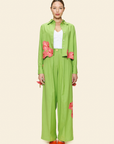 Person wearing a green outfit with floral details on a plain background