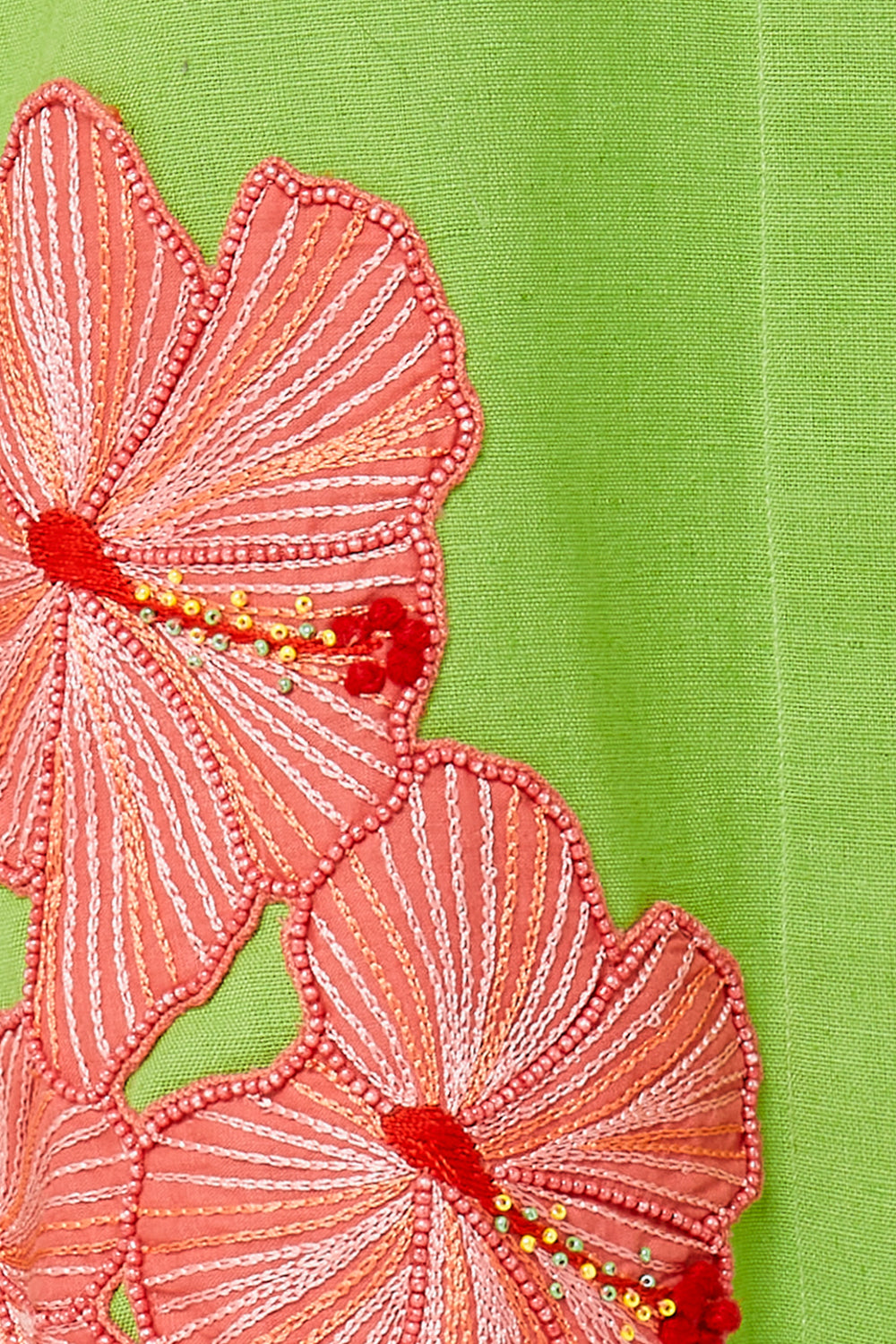 Embroidered pink flowers with red centers on a green fabric background