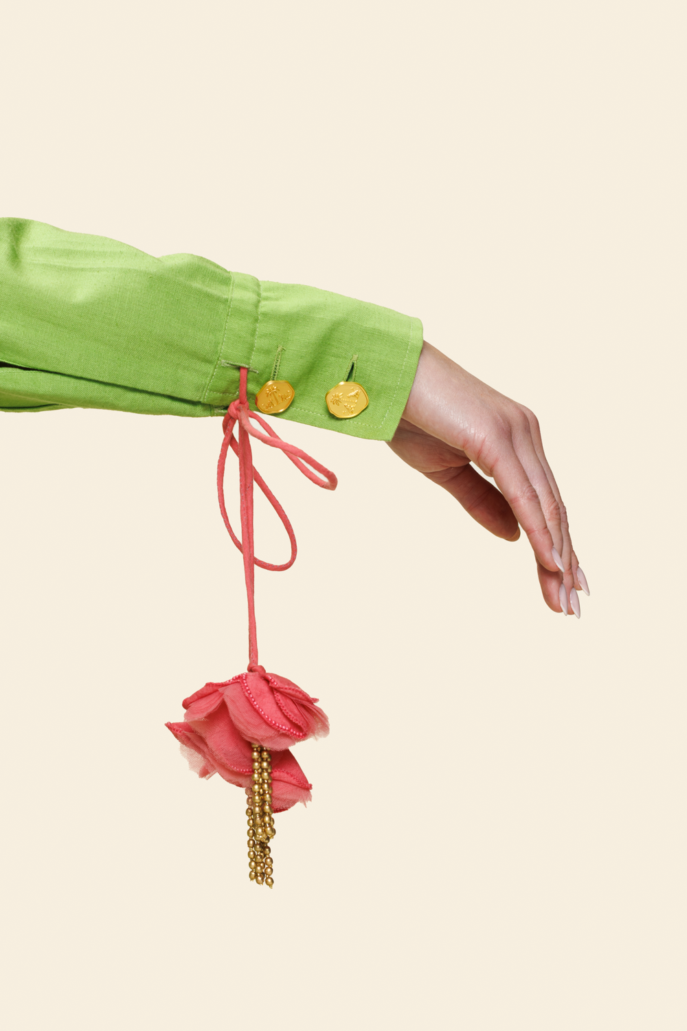 Hand holding a pink floral keychain against a light beige background.
