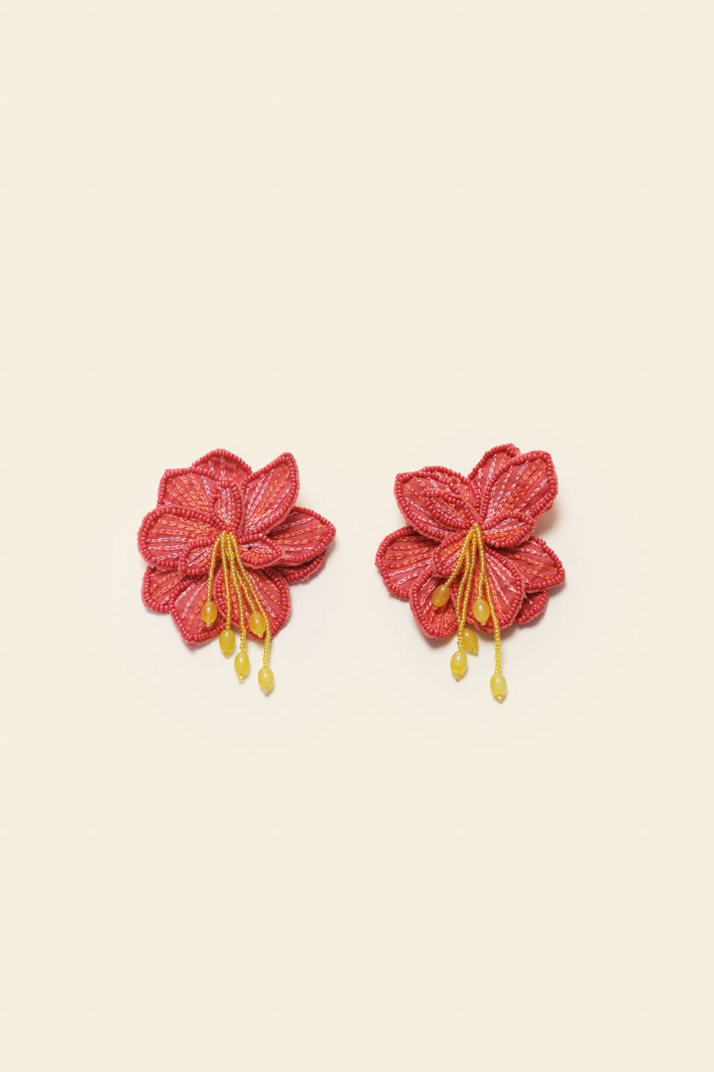 Pair of red floral earrings on a beige background