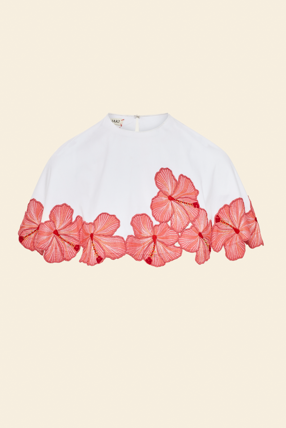 White top with coral pink floral trim on a beige background