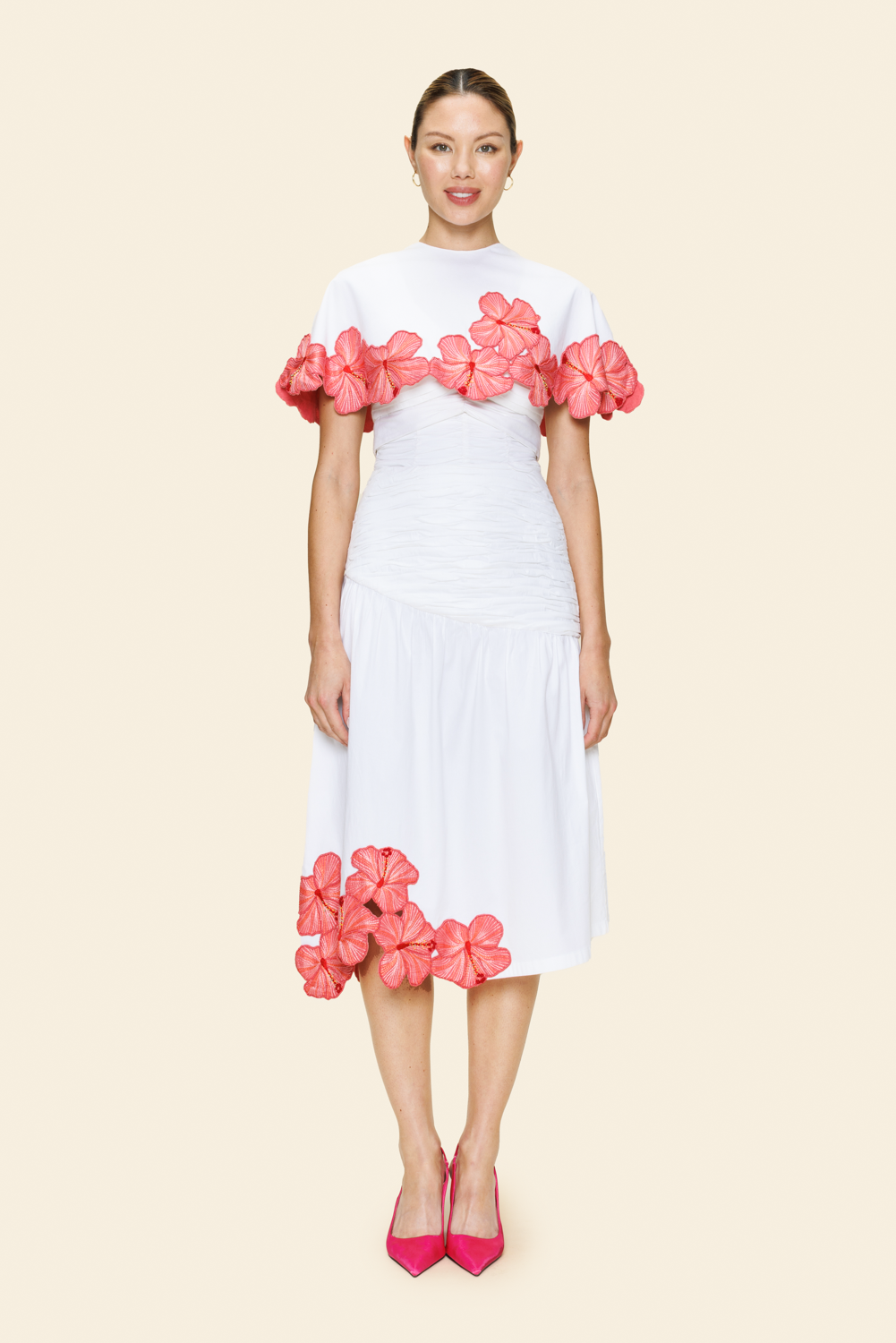 Woman wearing a white skirt and cape with pink floral embellishments on a beige background