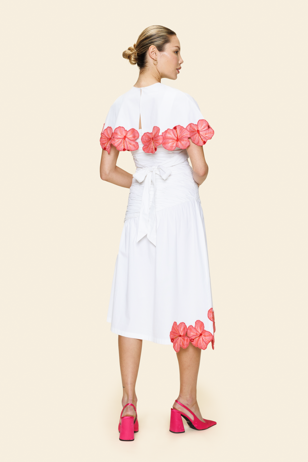 Woman wearing a white skirt and cape with pink floral details 