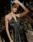 Woman wearing a floral dress standing outdoors with greenery in the background