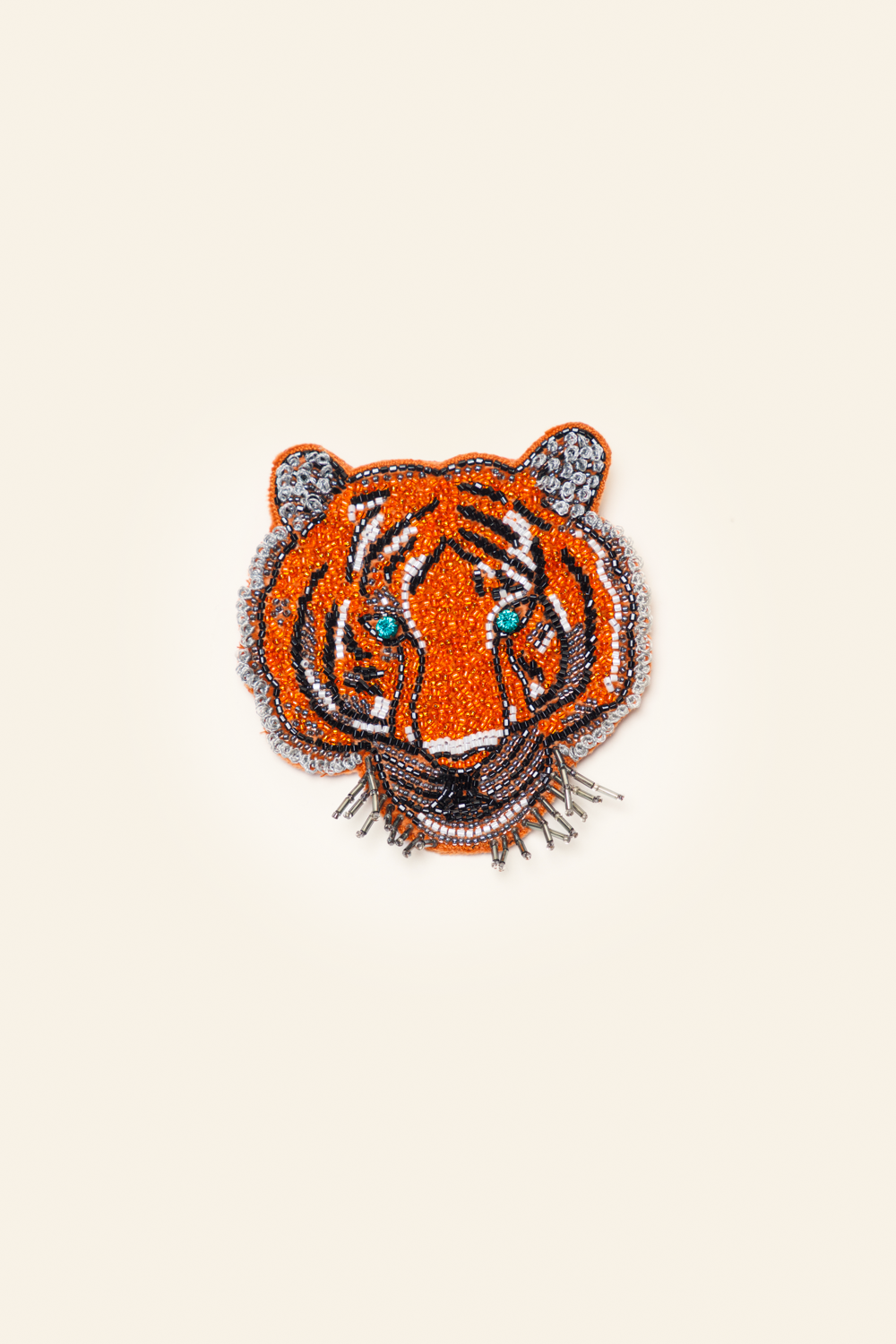 Embroidered tiger brooch on a beige background