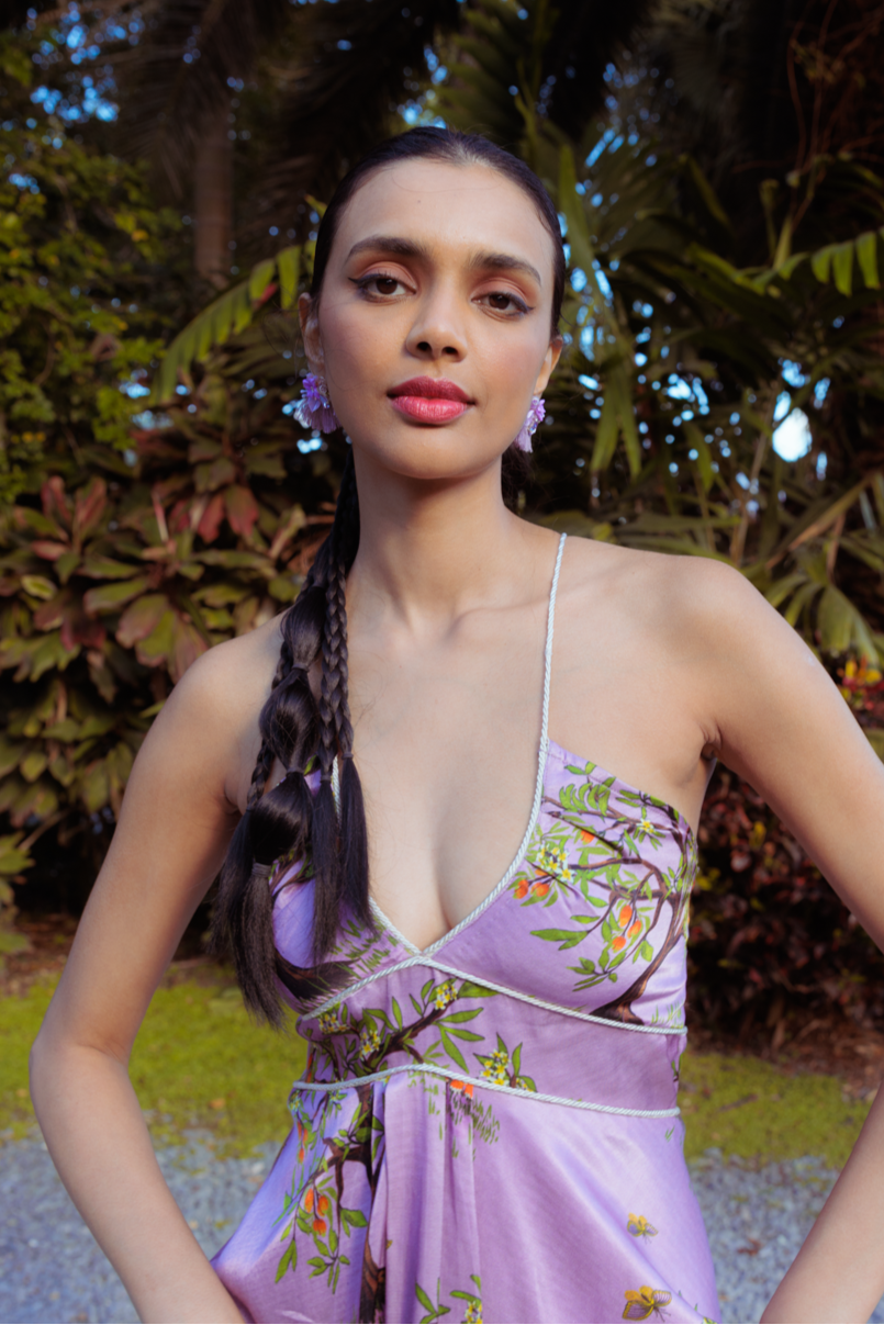 Woman wearing a purple floral dress with a garden background