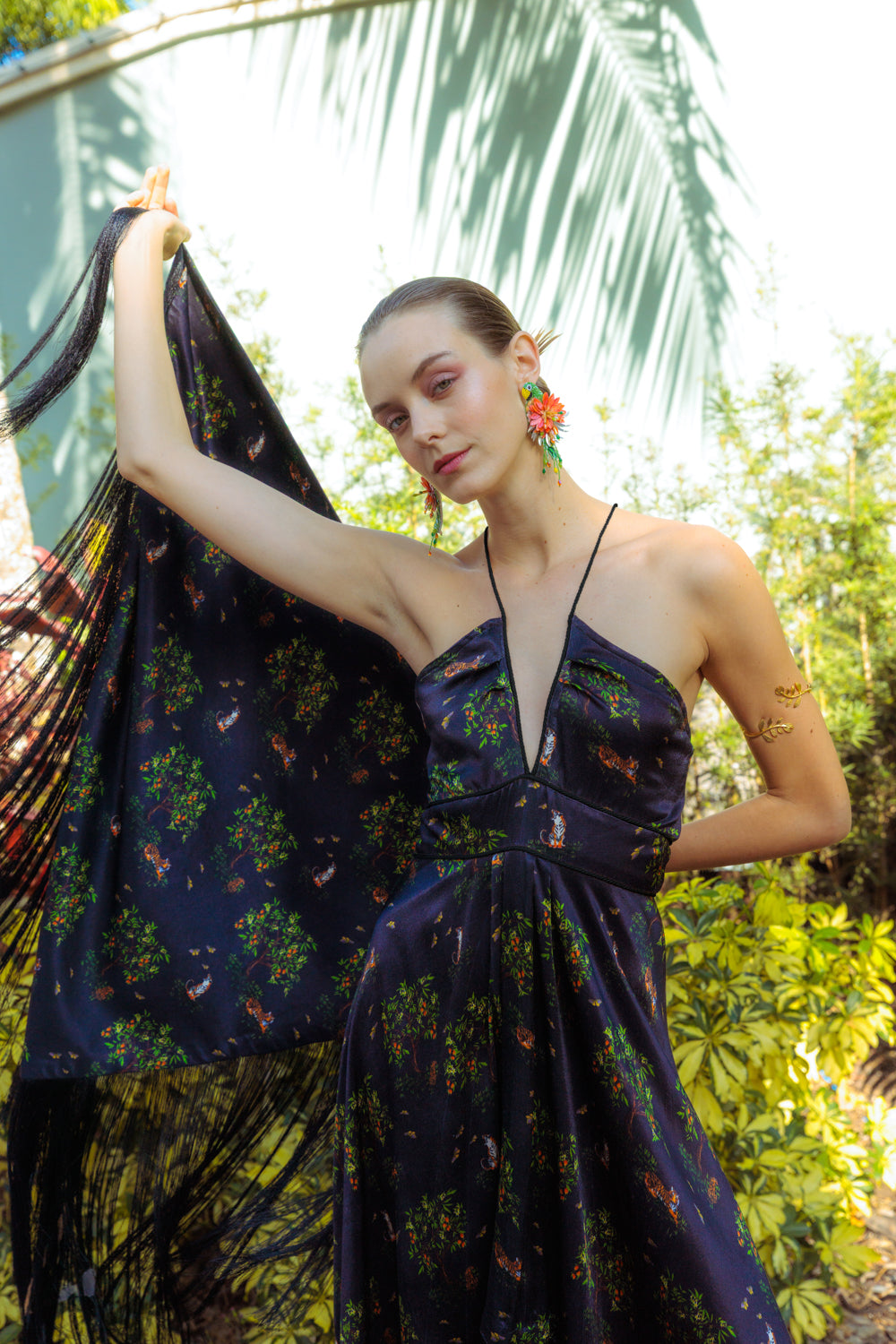Woman in a floral dress holding a patterned fabric against a natural background