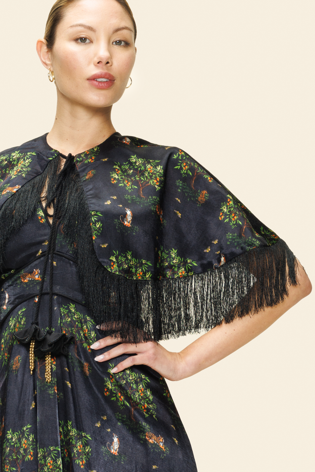 Woman wearing a dark floral dress with fringe details.