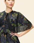 Woman wearing a dark floral dress with fringe details.