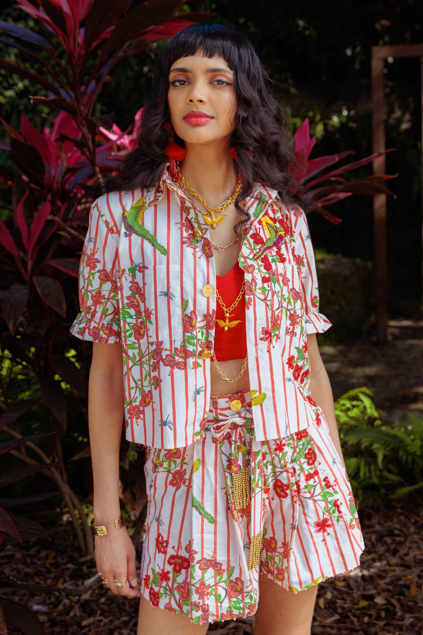 A woman wearing a colorful floral outfit with florals in the background