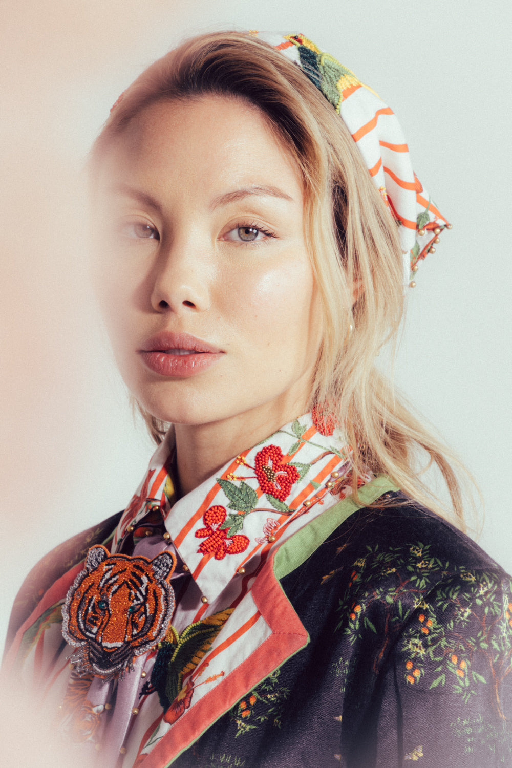 Woman wearing a patterned scarf with a tiger design on a plain background