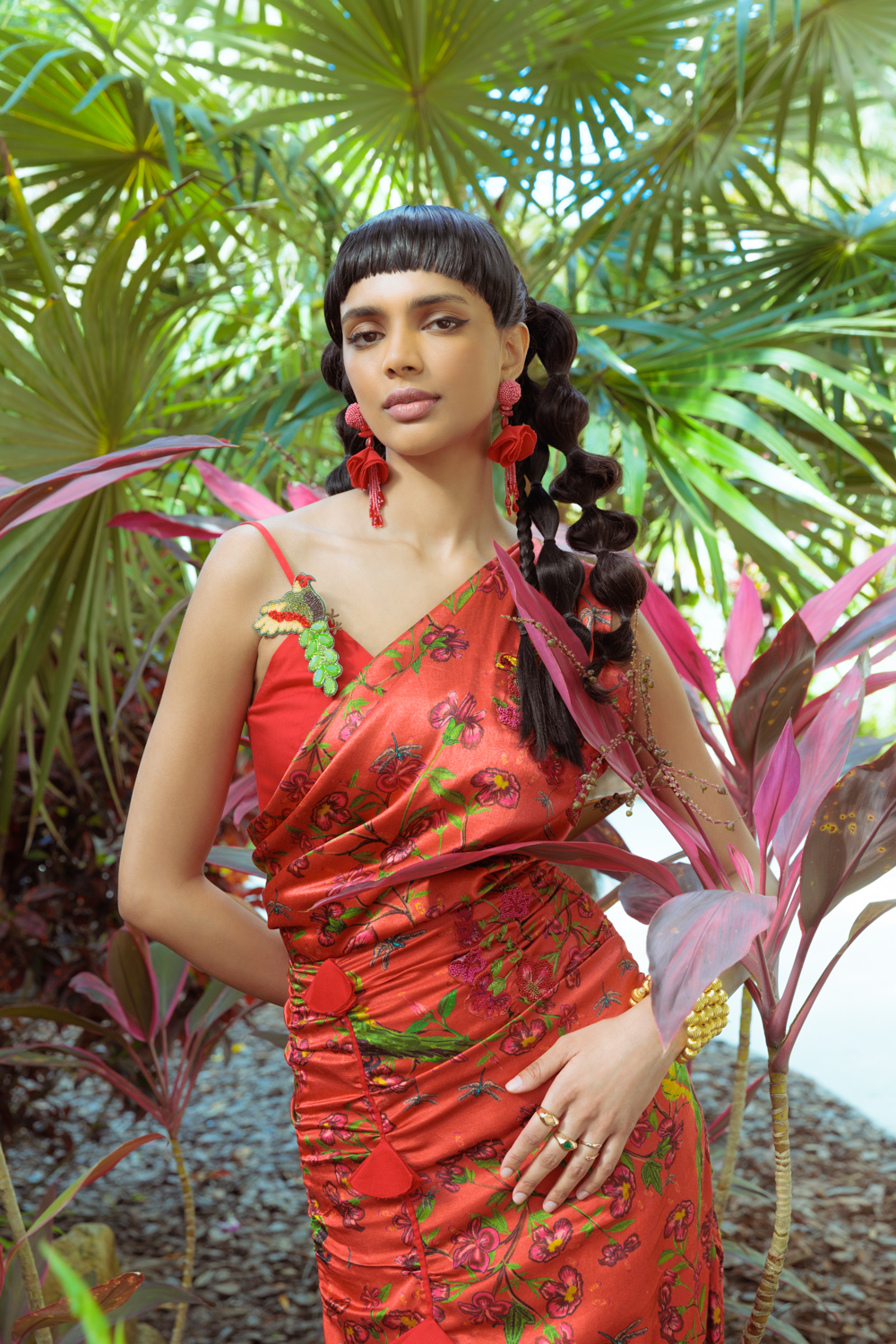 Woman in a red floral dress standing among tropical plants