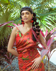 Woman in a red floral dress standing among tropical plants