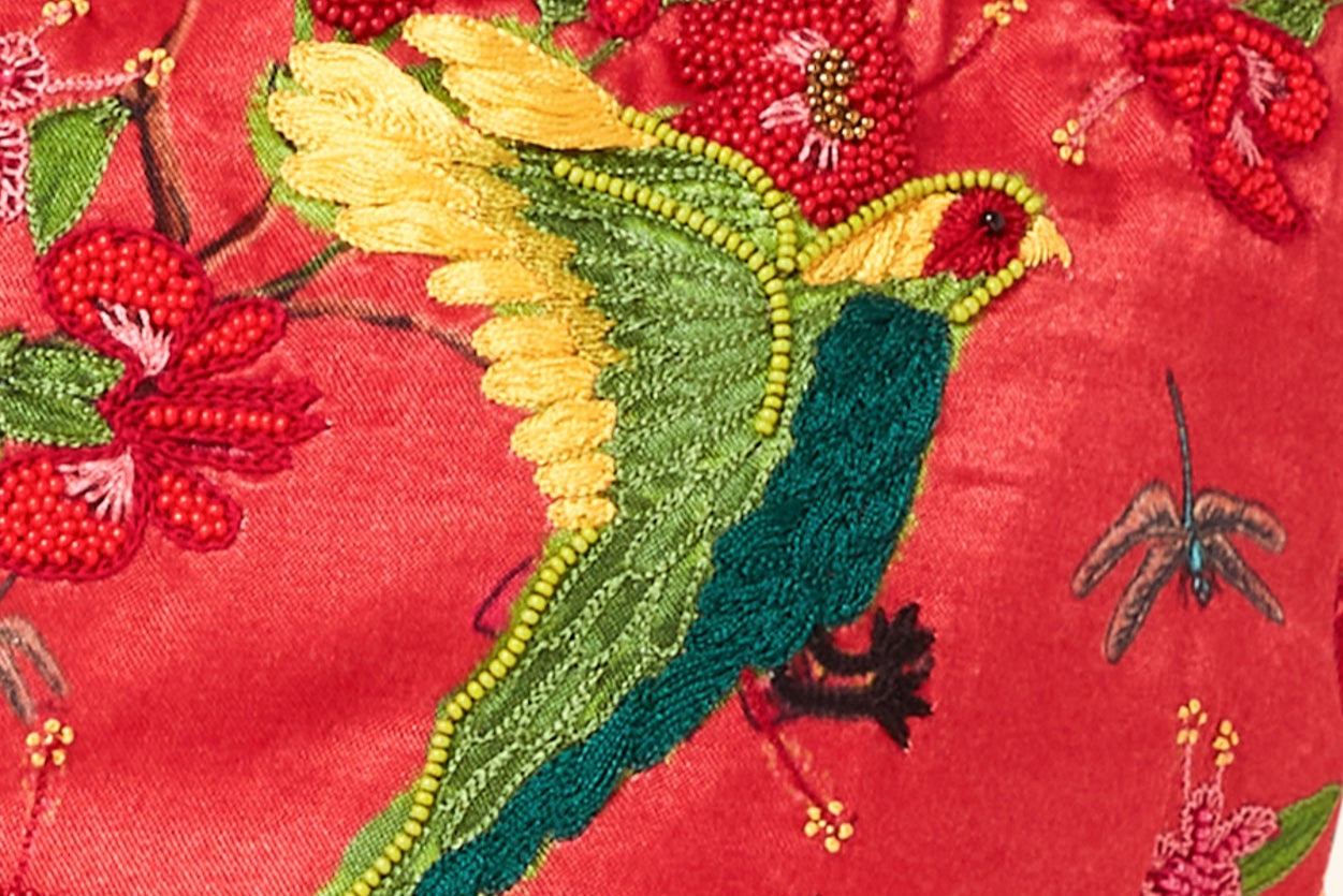 Embroidered fabric with a bird and floral design on a red background