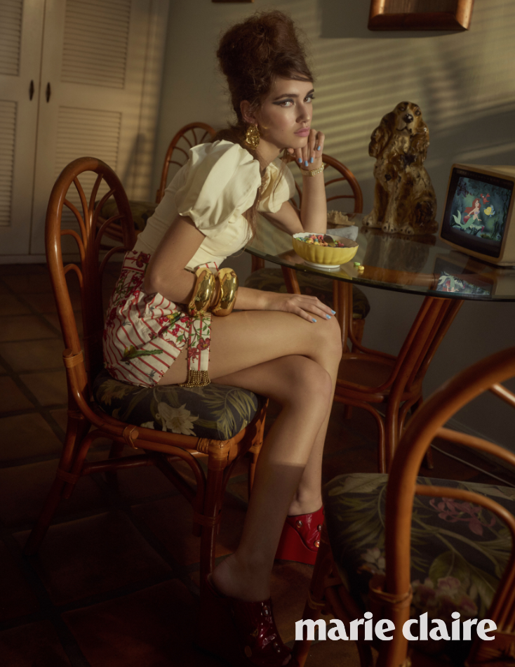 Woman sitting at a table with Ashaki red shorts with a vintage setting, featuring a small television.