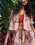 video of woman wearing red striped floral shirt and short, surrounded by palmtrees and florals