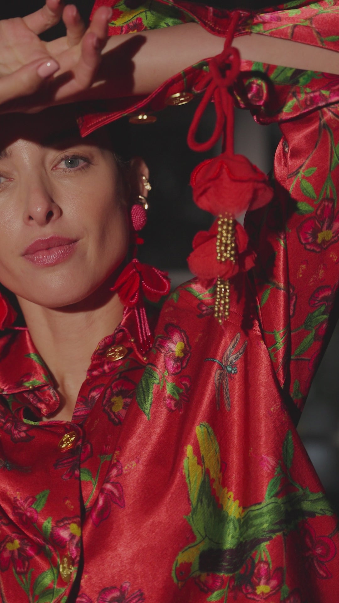 Lady in red suit dancing with tassels against a dark background