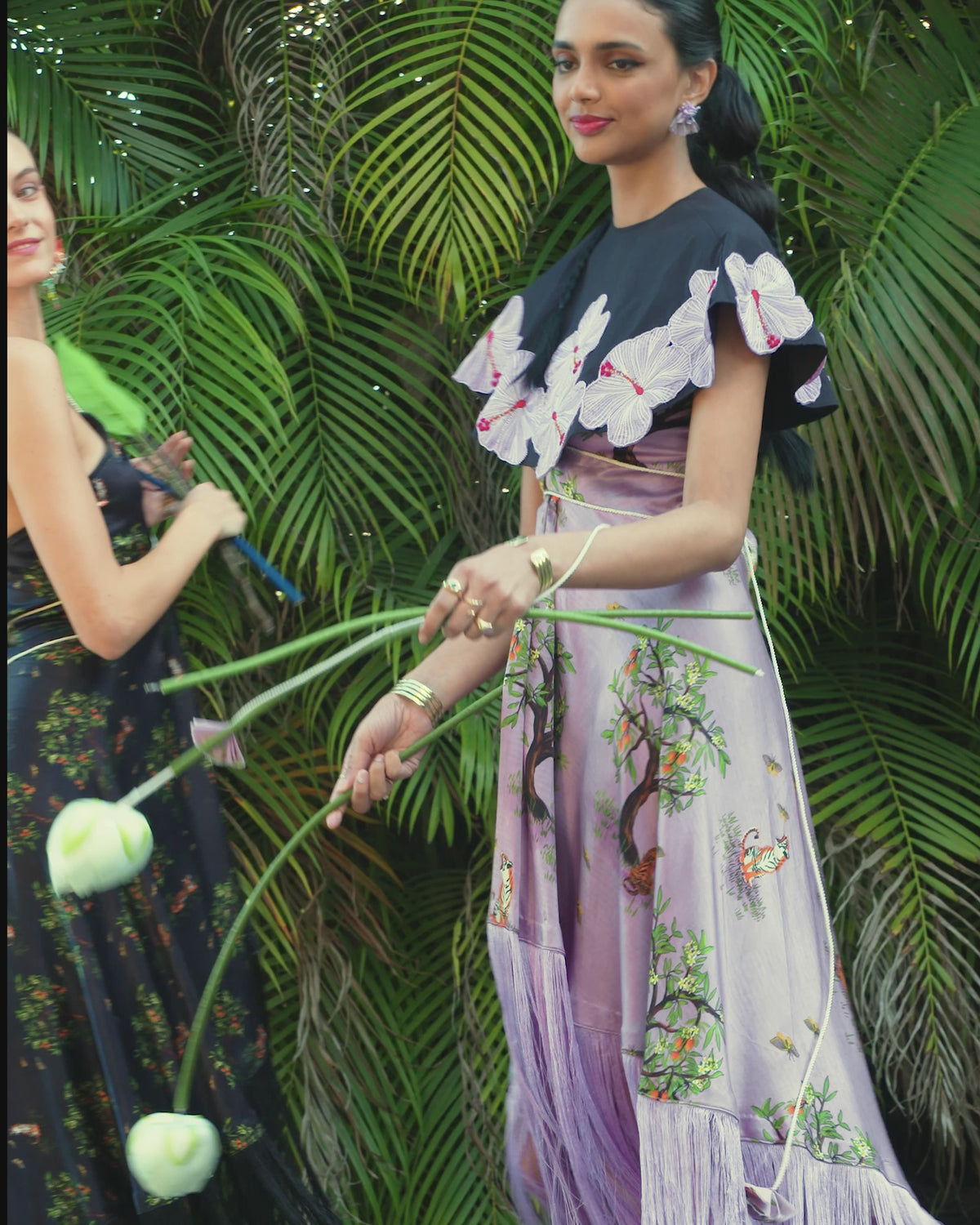 Two women in printed dresses dancing in tropical setting