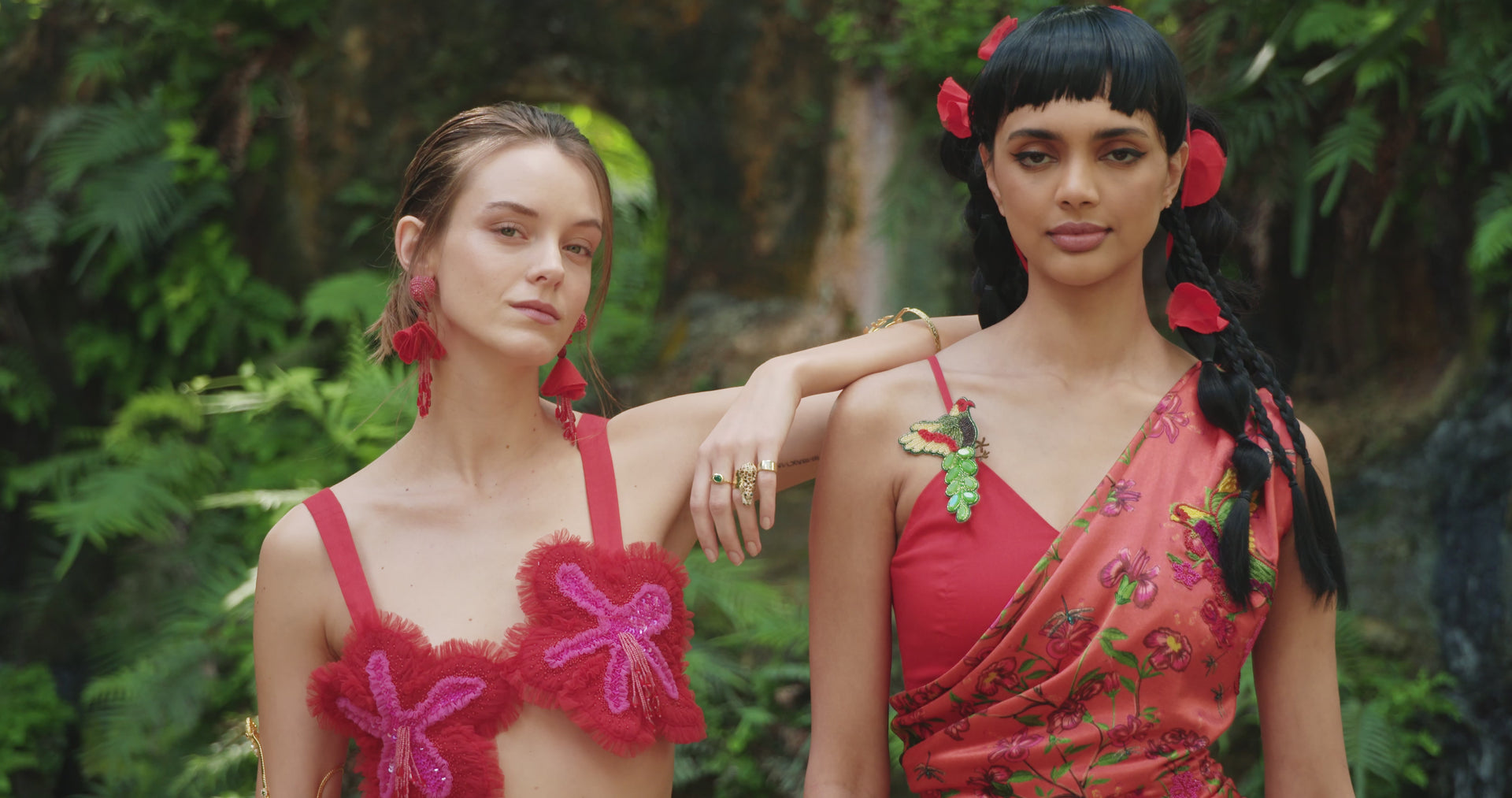 Two women dressed in red outfits standing in tropical environment